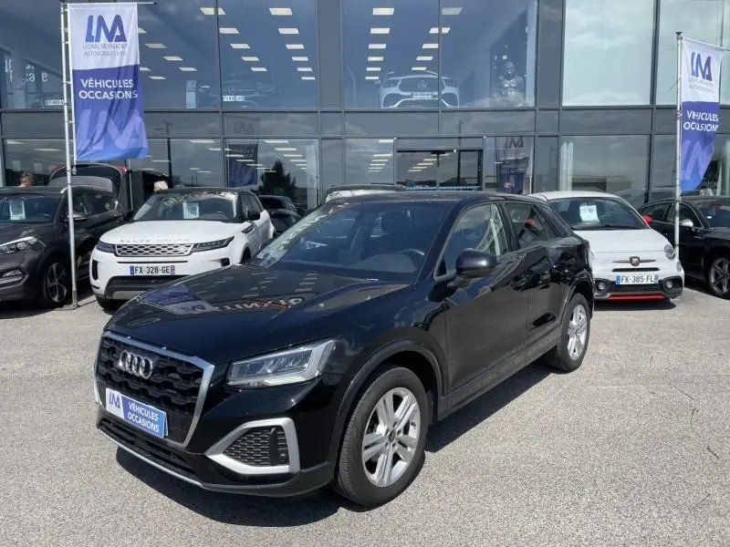 Audi Q2 TFSI 150CV noir métal vue 3/4 avant droit, avec calandre hexagonale et jantes argentées, stationné devant un showroom.