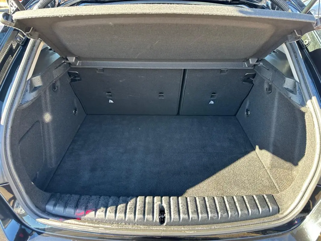 Coffre ouvert vu de l'arrière d'une BMW Série 1 F40 118d noire, espace de chargement propre et vide.