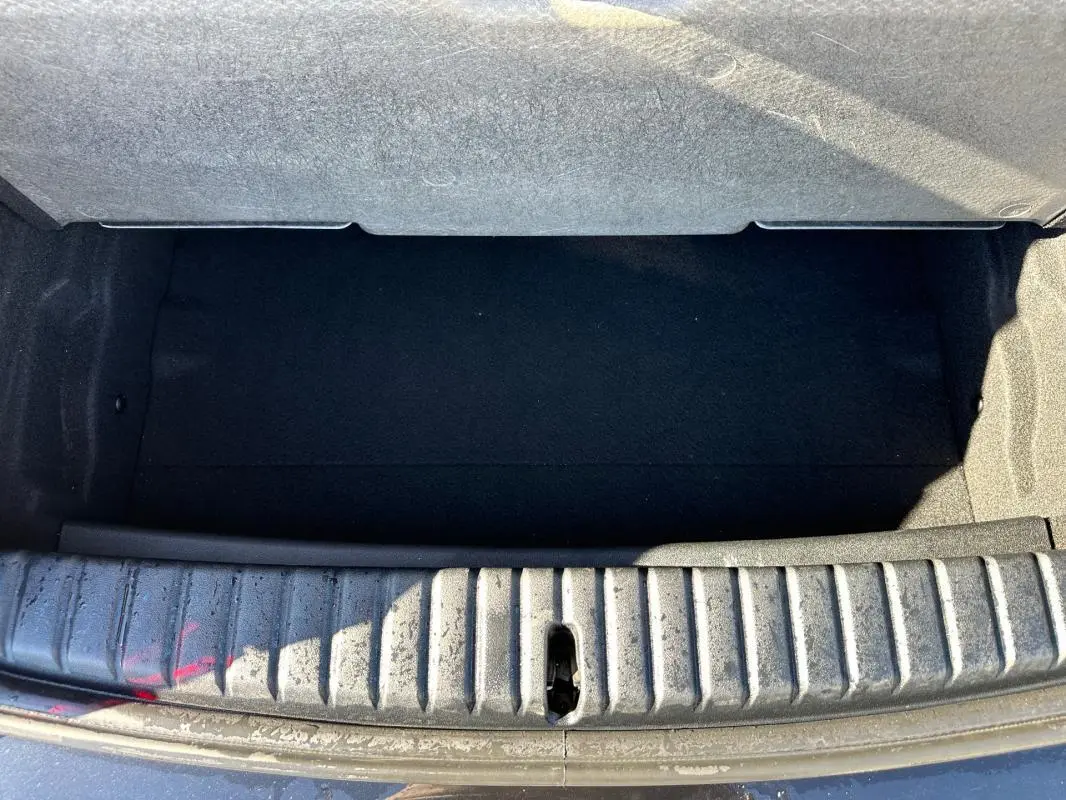 Coffre ouvert vu de dessus d'une BMW Série 1 F40 noire, montrant l'espace de chargement vide et le seuil d'entrée.