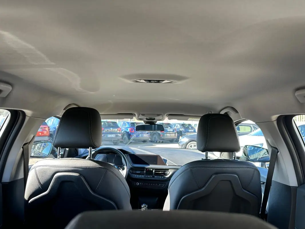 Vue intérieure arrière de la BMW Série 1 noire F40 118d 2021, avec sièges en cuir et tableau de bord moderne.