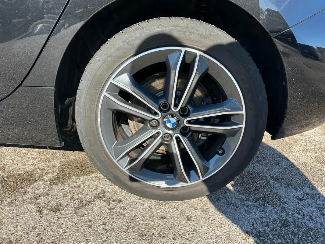 Gros plan sur la jante alliage 17 pouces noire d'une BMW Série 1 F40 118d, avec logo BMW au centre.