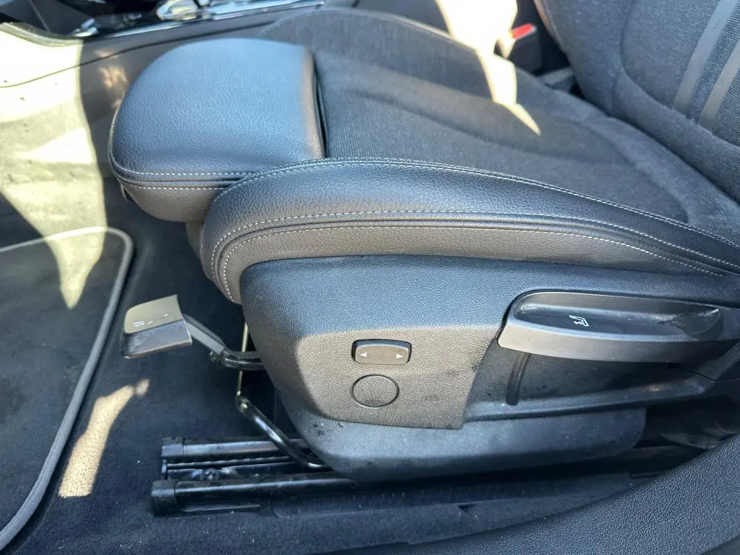 Détail du siège conducteur noir de la BMW Série 1 F40 118d 2021 avec réglage manuel de l'inclinaison et accoudoir central.