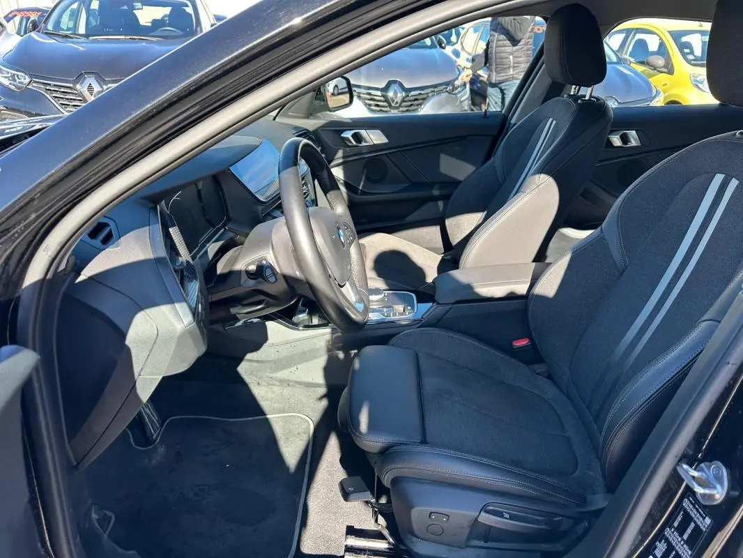 Intérieur BMW Série 1 F40 118d noir, vue côté conducteur montrant sièges sport et tableau de bord moderne.