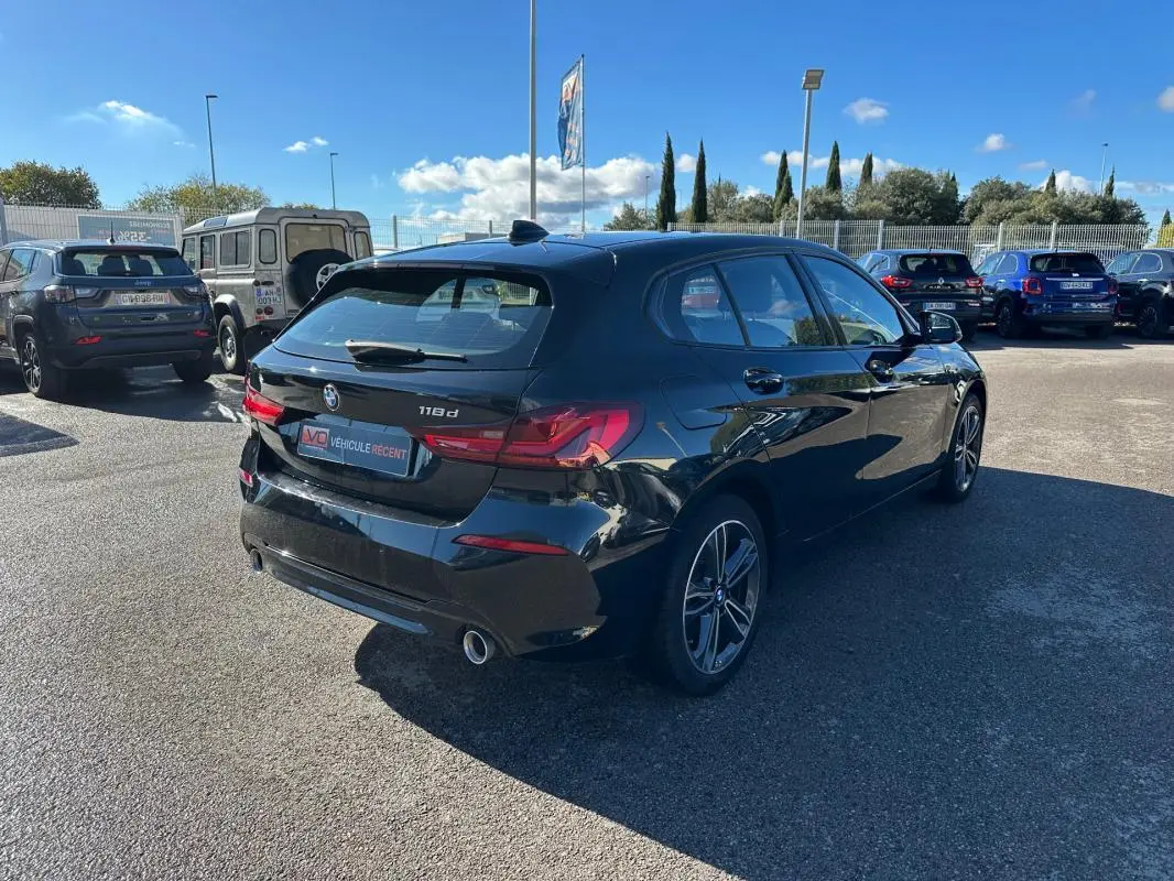 BMW Série 1 F40 118d noire vue en 3/4 arrière droit, avec jantes alliage 17 pouces et double sortie d’échappement.