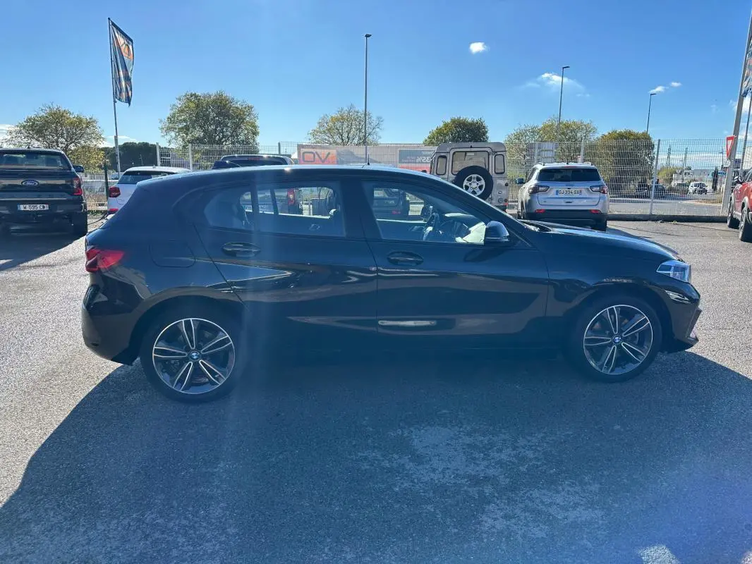 BMW Série 1 F40 118d noire vue de profil côté gauche, avec jantes alliage 17 pouces et toit ouvrant panoramique.