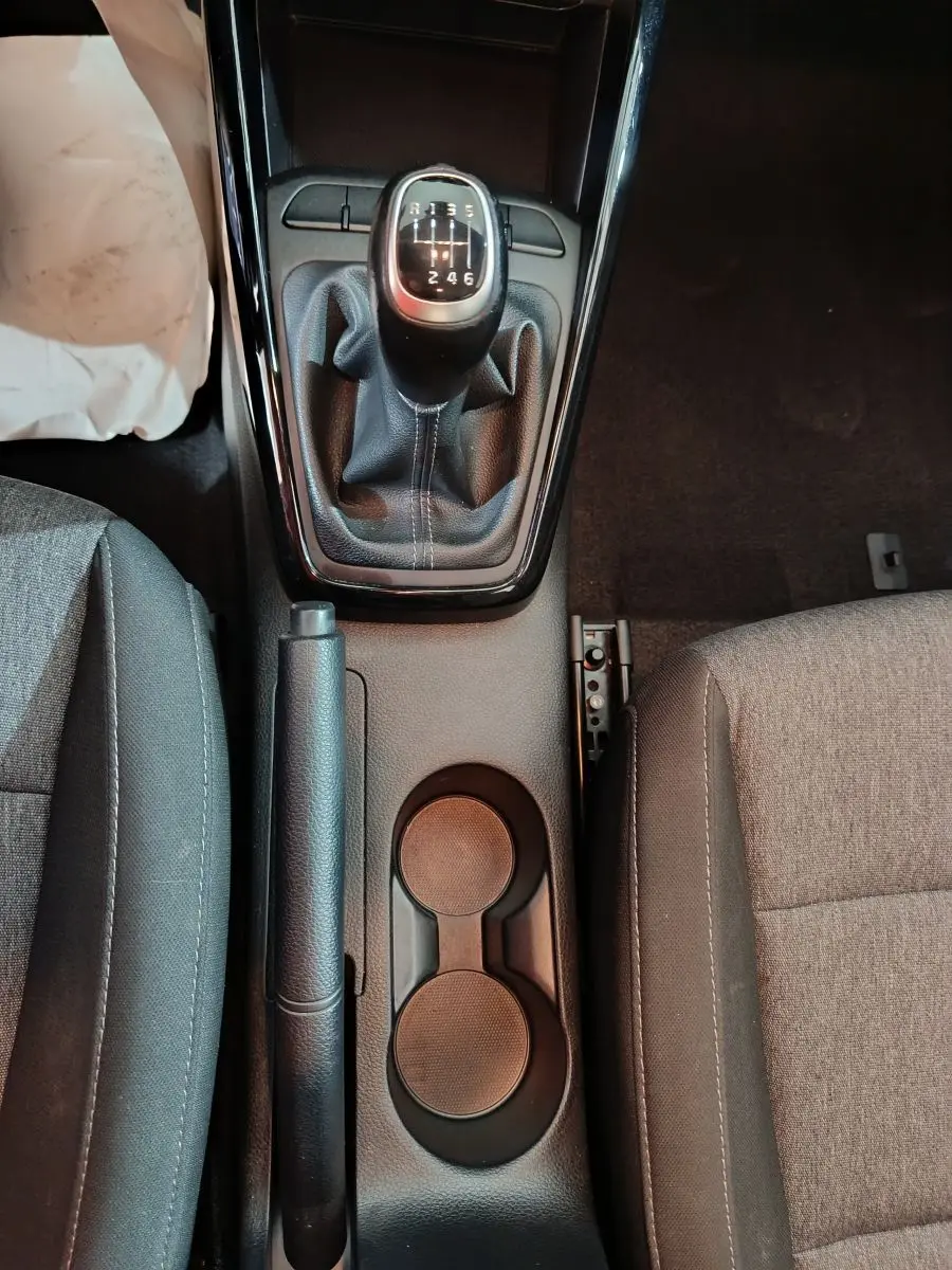 Vue plongeante sur la console centrale intérieure du KIA Stonic gris clair, montrant levier de vitesses manuel et frein à main.