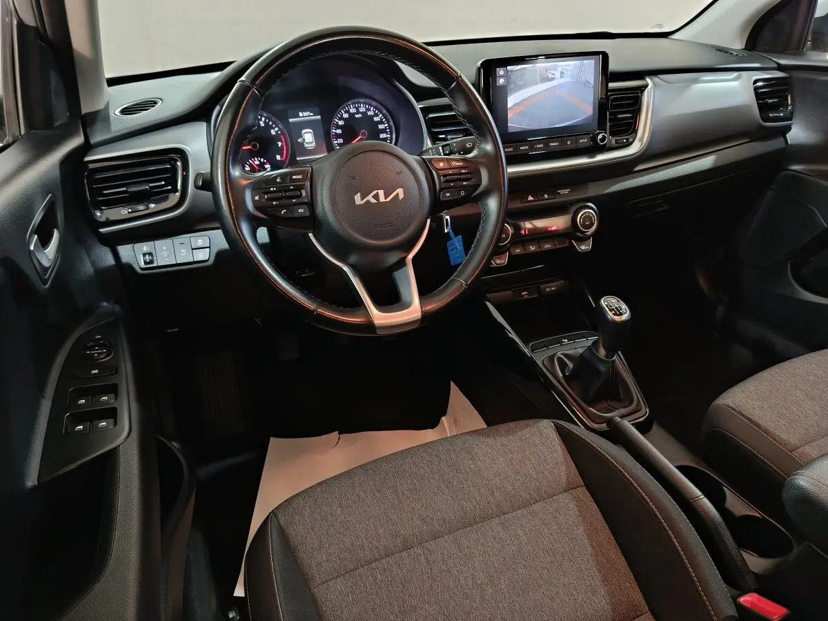 Vue intérieure avant du tableau de bord et volant noir de la KIA Stonic 1.0 T-GDI avec écran tactile et boîte manuelle.