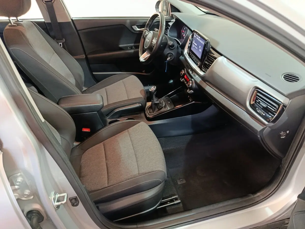 Vue intérieure côté conducteur du Kia Stonic gris clair 2022, avec tableau de bord moderne et boîte manuelle visible.