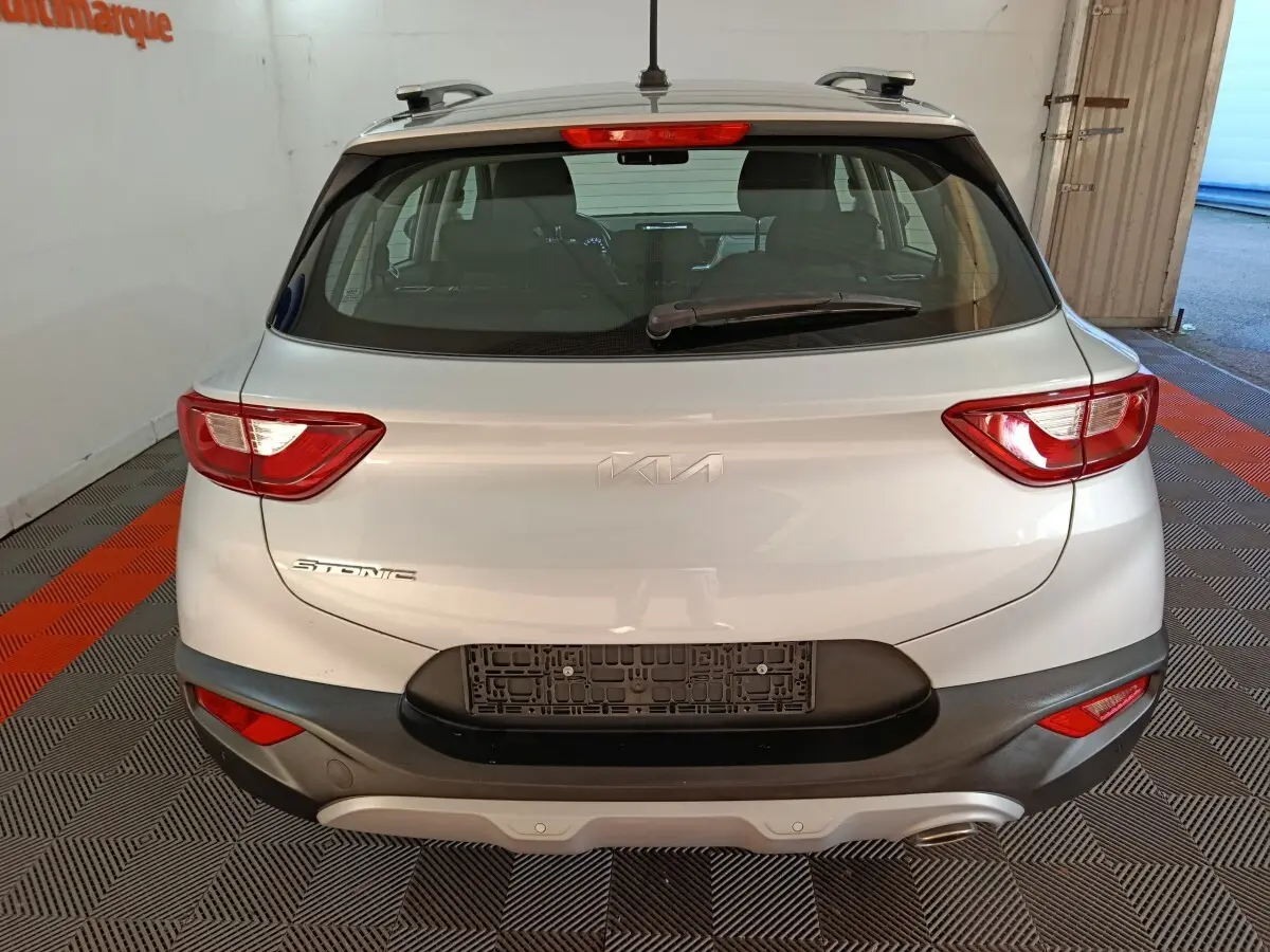 Vue arrière d'un KIA Stonic gris clair 2022 avec feux arrière allumés et pare-chocs noir contrastant.