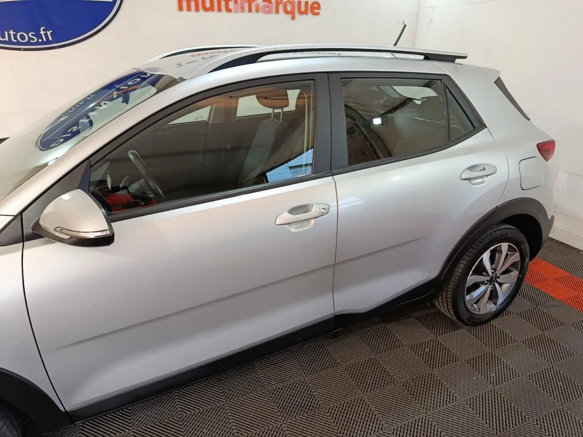 Vue de profil côté droit du KIA STONIC gris clair 2022, mettant en valeur les jantes alliage et les barres de toit.