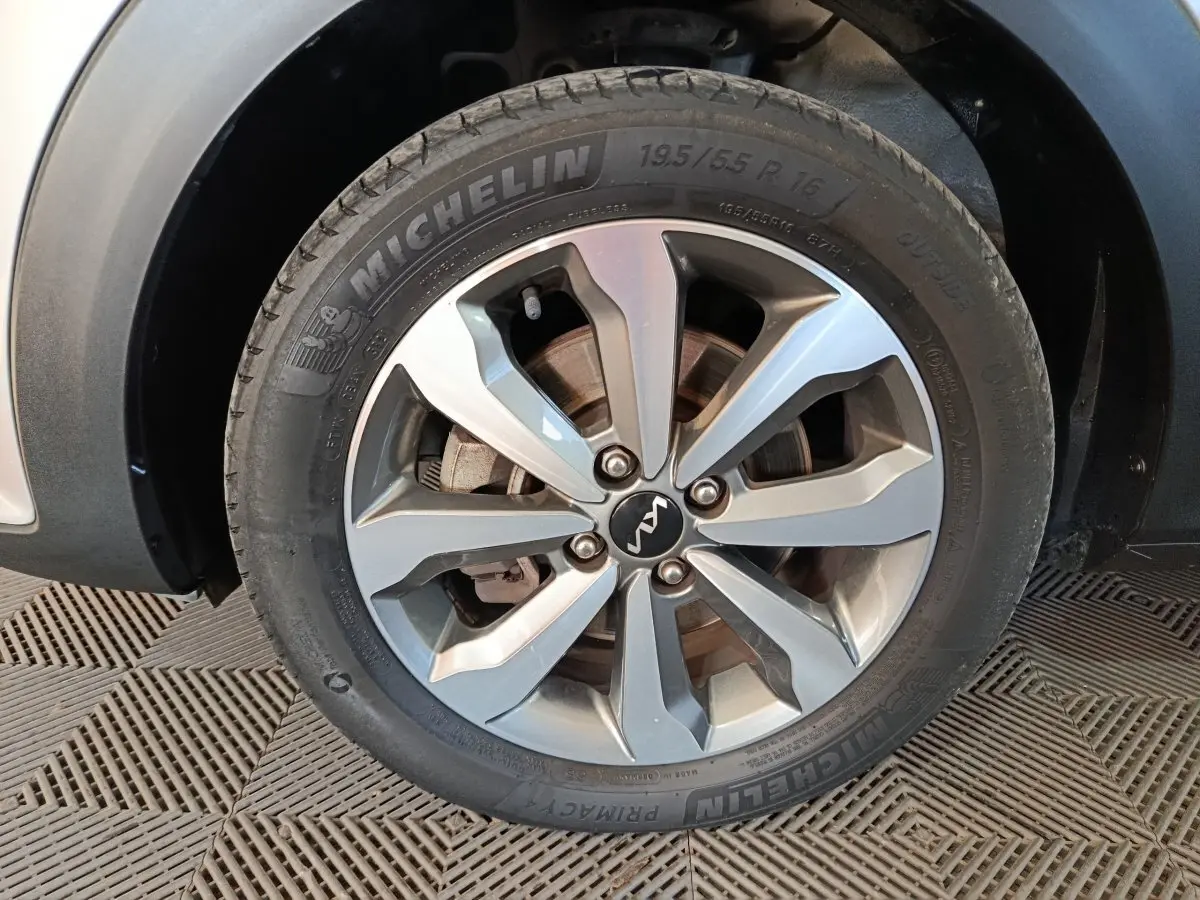 Gros plan sur la roue avant gauche d’un KIA STONIC gris clair, avec jante alliage et pneu Michelin visible.