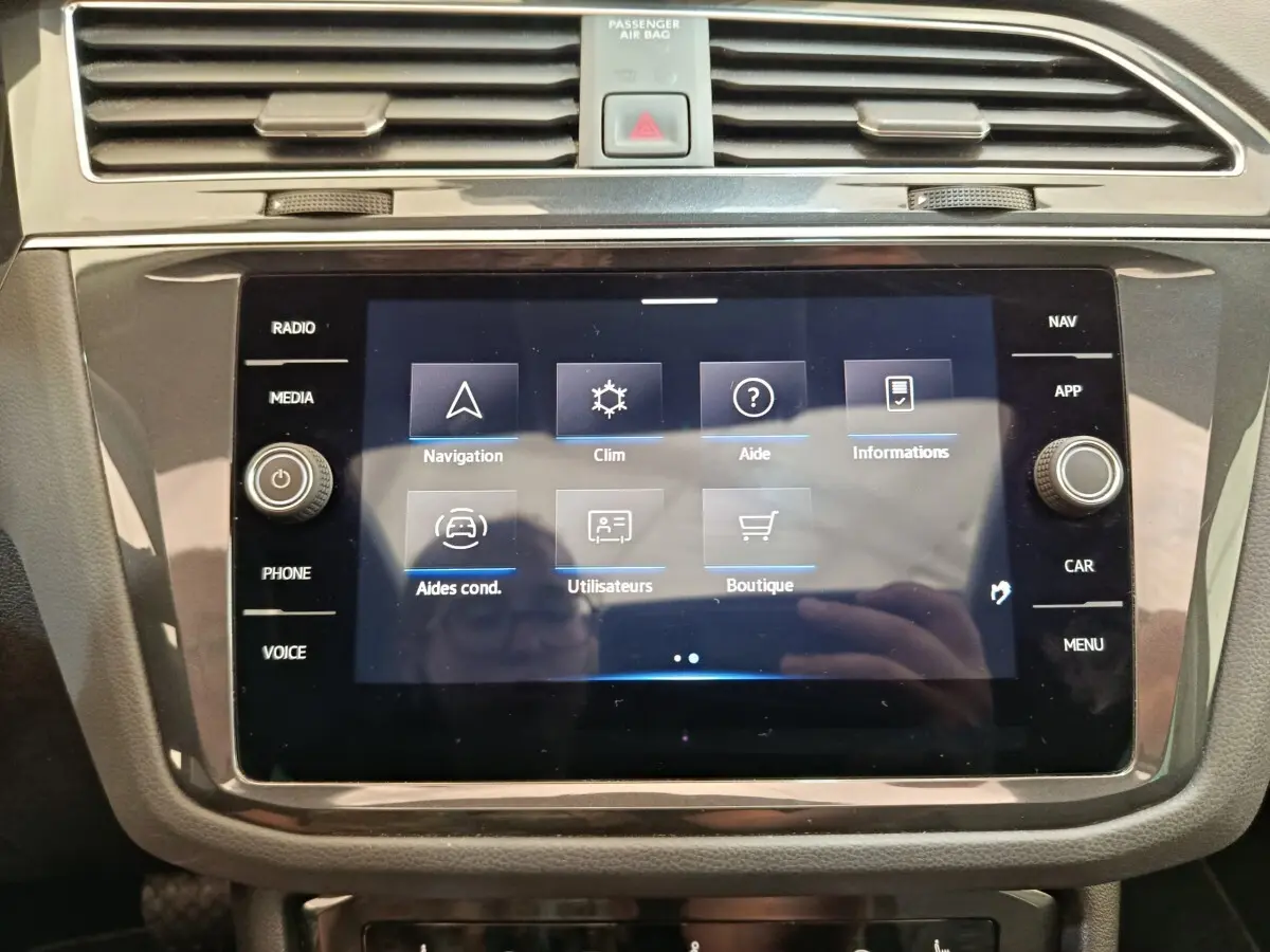 Écran tactile central du tableau de bord du Volkswagen Tiguan noir, affichant le menu de navigation et climatisation.