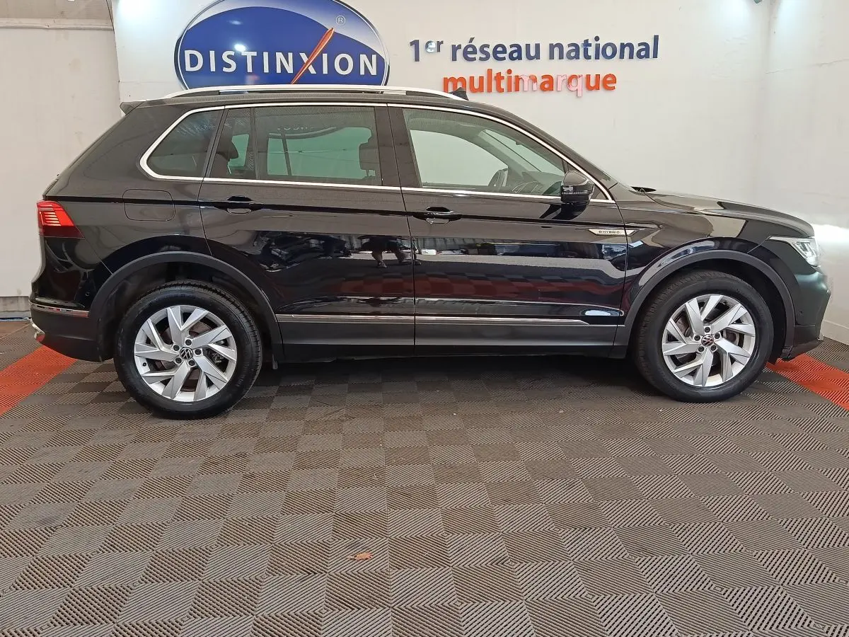 Profil côté gauche d’un Volkswagen Tiguan 1.4 eHybrid noir, avec badge hybride visible sur l’aile avant.