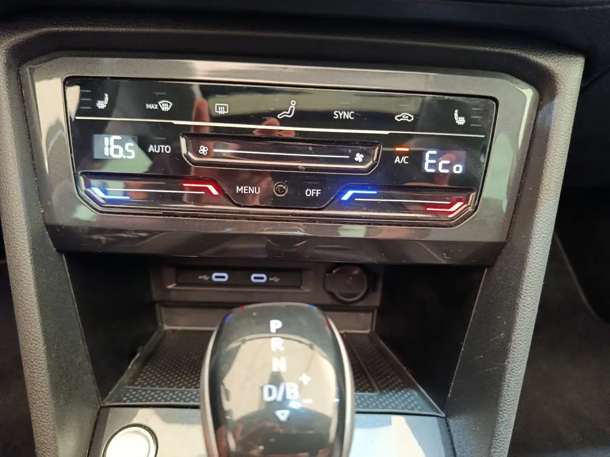 Gros plan sur la console centrale noire du Volkswagen Tiguan 1.4 eHybrid avec commandes climatisation digitale et levier de boîte auto.