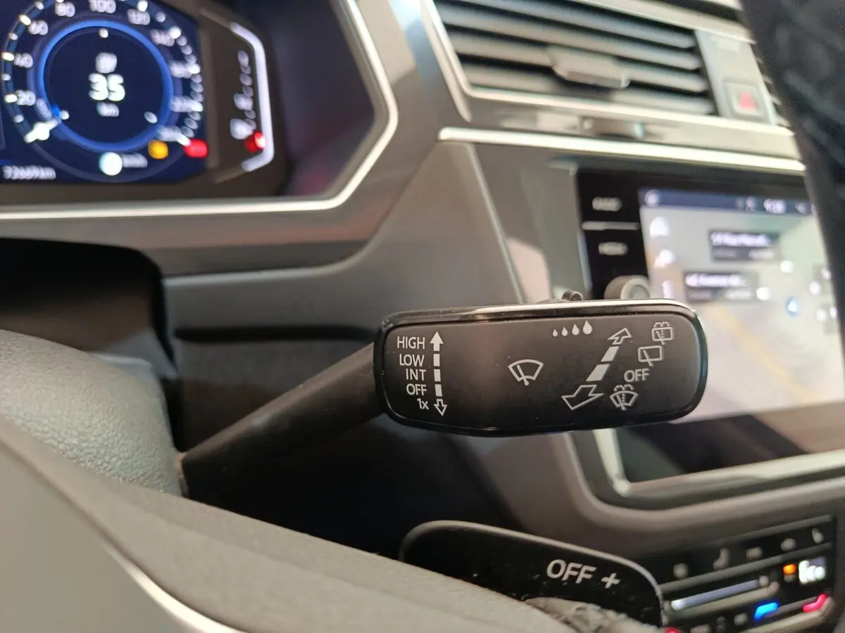 Gros plan sur la commande des essuie-glaces à gauche du volant dans l’habitacle noir du Volkswagen Tiguan 2022.