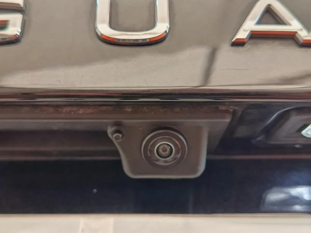 Gros plan sur la caméra de recul intégrée sous le coffre noir d’un Volkswagen Tiguan hybride rechargeable.