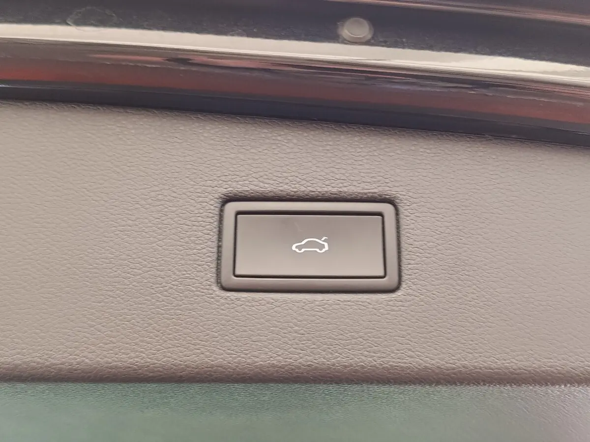 Bouton d'ouverture électrique du coffre sur la garniture intérieure d'un Volkswagen Tiguan noir, vue rapprochée.