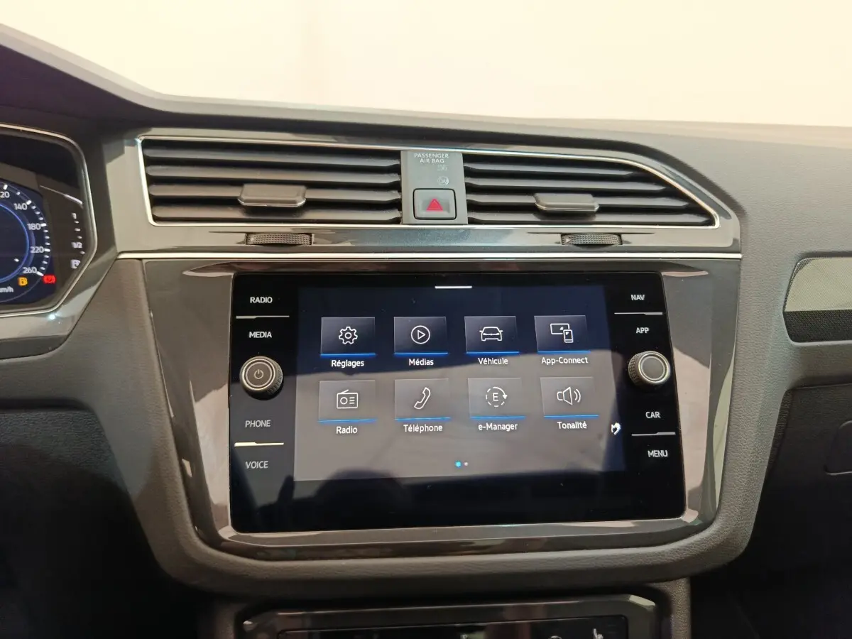 Vue rapprochée du tableau de bord noir du Volkswagen Tiguan 1.4 eHybrid 2022 avec écran tactile central allumé.