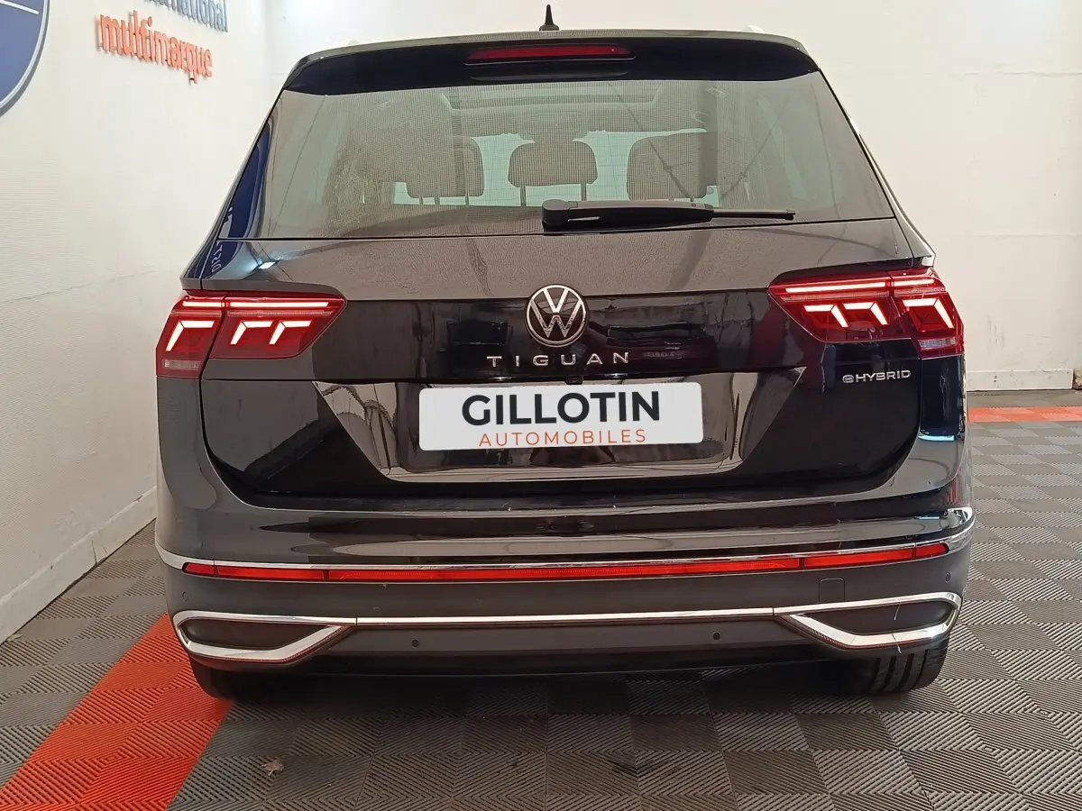 Vue arrière d'un Volkswagen Tiguan noir hybride rechargeable avec feux LED distinctifs et logo central visible.