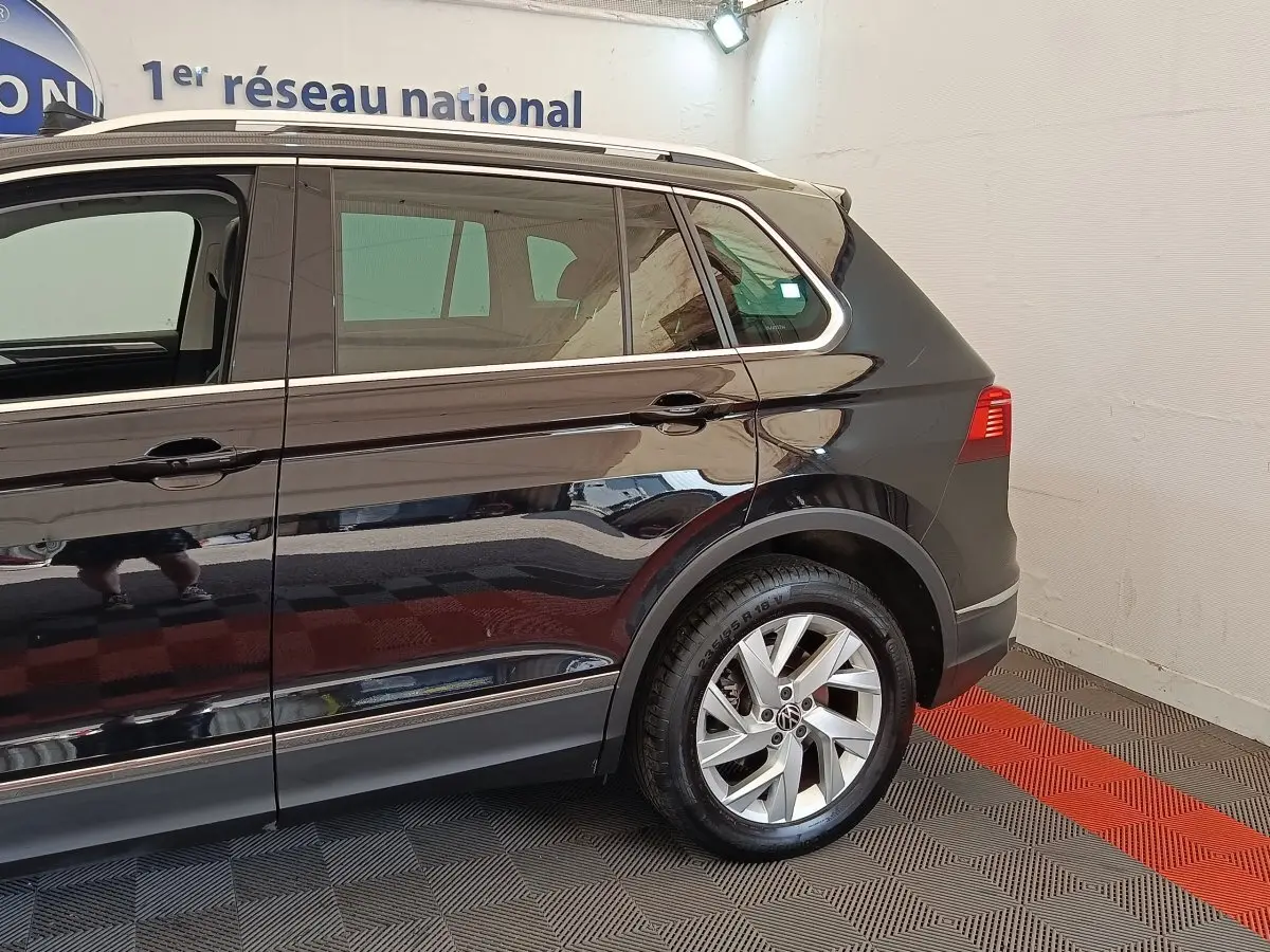 Vue latérale droite du Volkswagen Tiguan noir 2022, mettant en valeur la roue arrière et les vitres teintées.