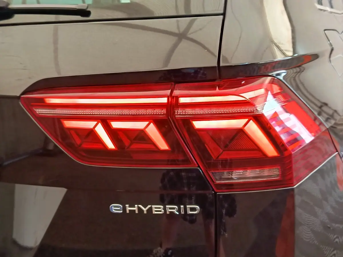 Gros plan sur le feu arrière droit rouge et le logo eHybrid d’un Volkswagen Tiguan noir 2022.