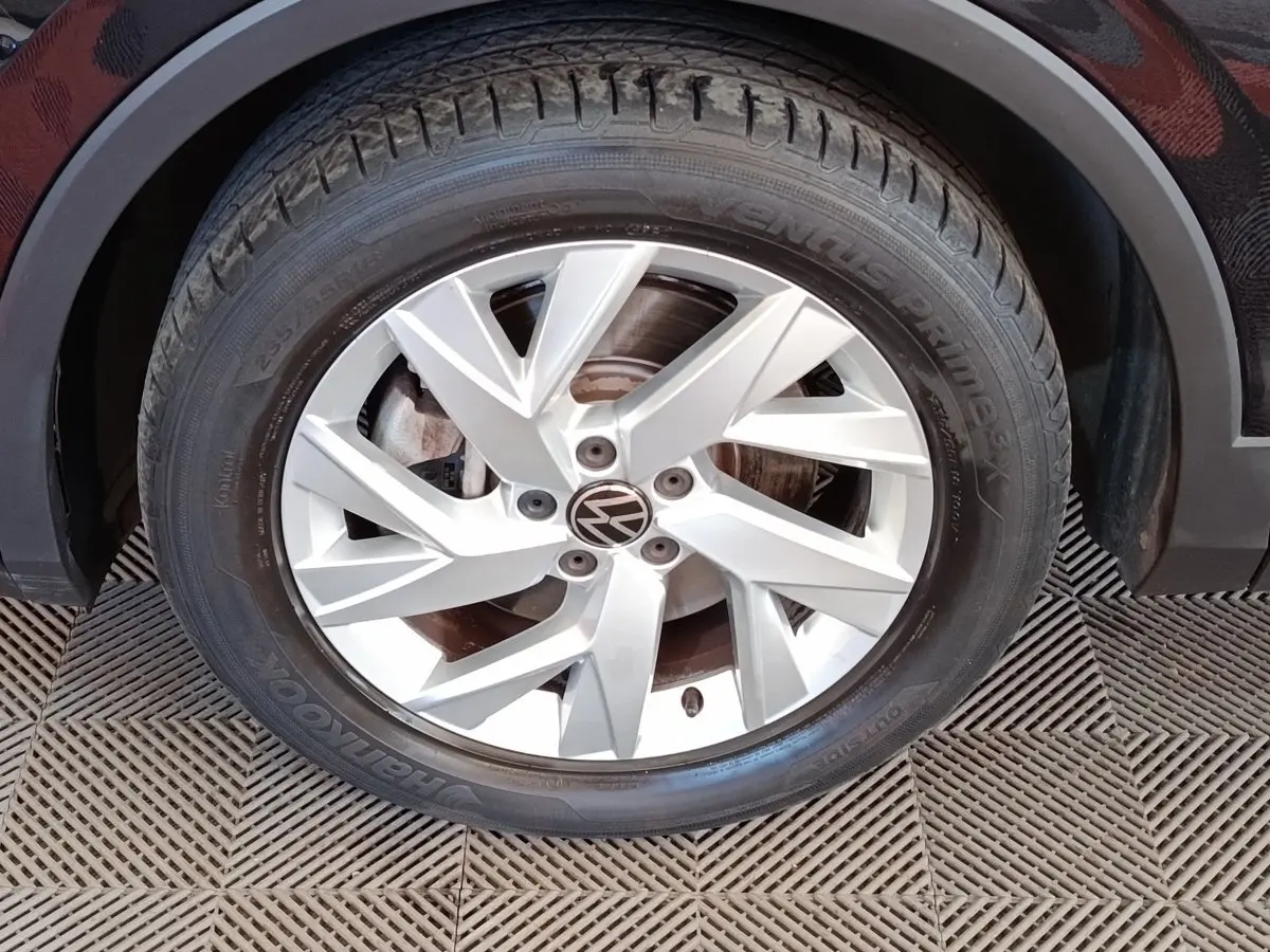 Gros plan sur la roue avant droite du Volkswagen Tiguan noir, mettant en valeur la jante alliage argentée à cinq branches doubles.