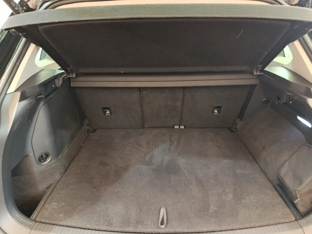 Coffre ouvert du Volkswagen Tiguan noir, vue intérieure arrière montrant l'espace de chargement et la tablette de séparation.