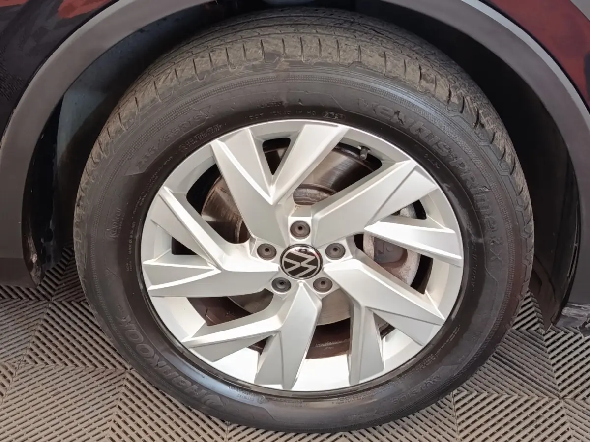 Gros plan sur la jante argentée à design géométrique du Volkswagen Tiguan noir, roue avant droite visible.