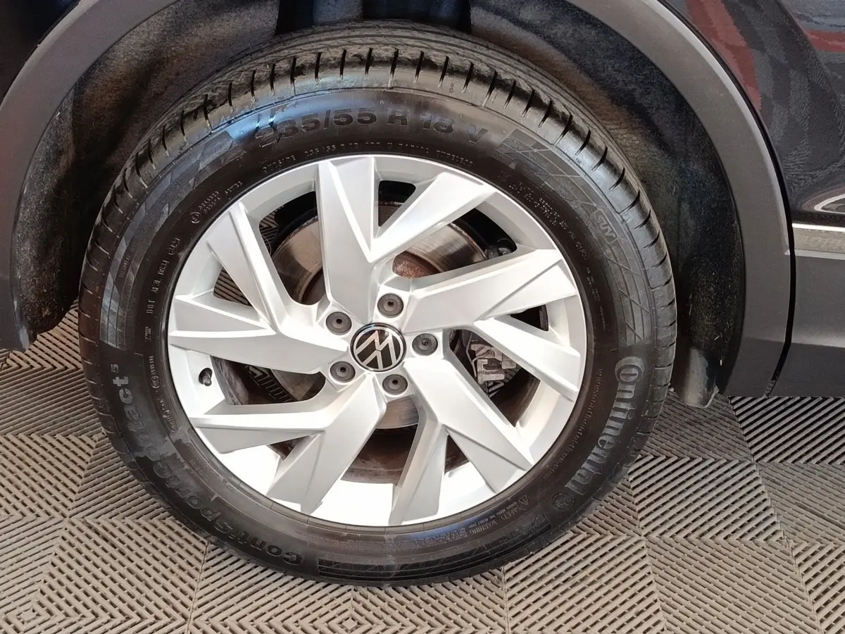 Gros plan sur la roue avant droite avec jante argentée du Volkswagen Tiguan noir 1.4 eHybrid 2022.