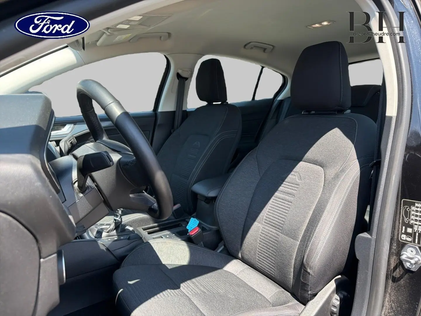 Vue intérieure côté conducteur de la Ford Focus 1.0 Flexifuel 2021 avec sièges tissu gris et volant cuir noir.