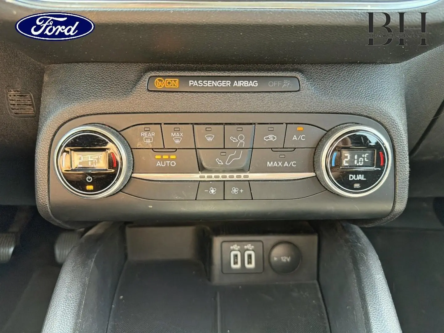 Vue rapprochée de la console centrale de la Ford Focus 1.0 Flexifuel 2021, montrant les commandes de climatisation bi-zone et ports USB.