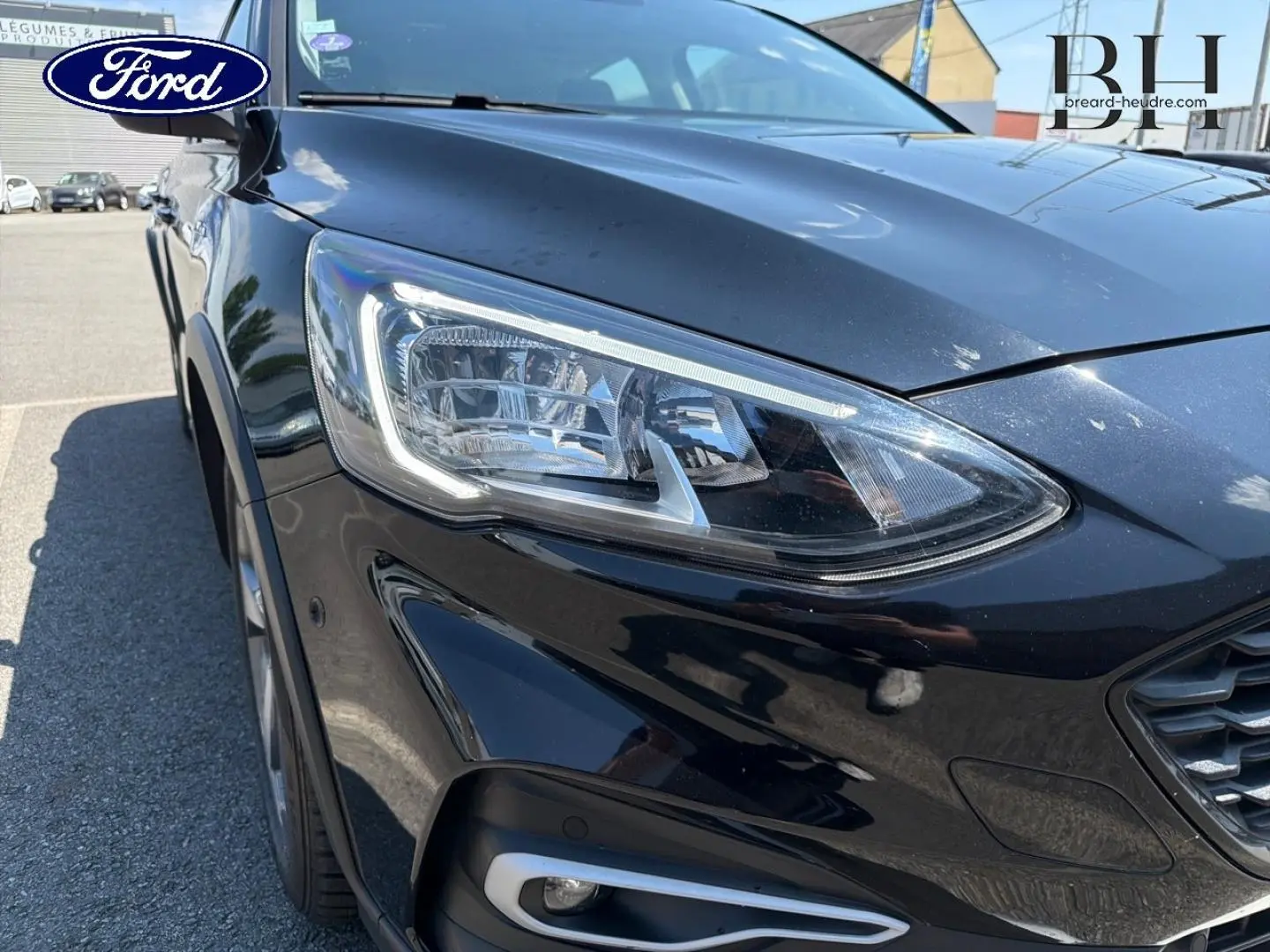 Gros plan sur l'avant droit noir métallisé de la Ford Focus avec son phare LED et calandre visible.