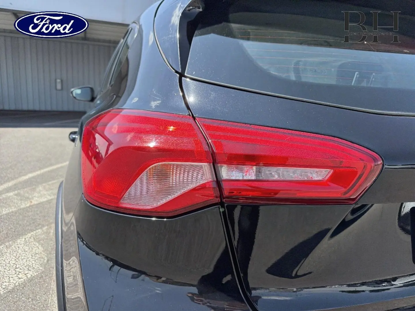 Gros plan sur le feu arrière droit d'une Ford Focus noire Agate métallisé, soulignant la finition et la carrosserie brillante.