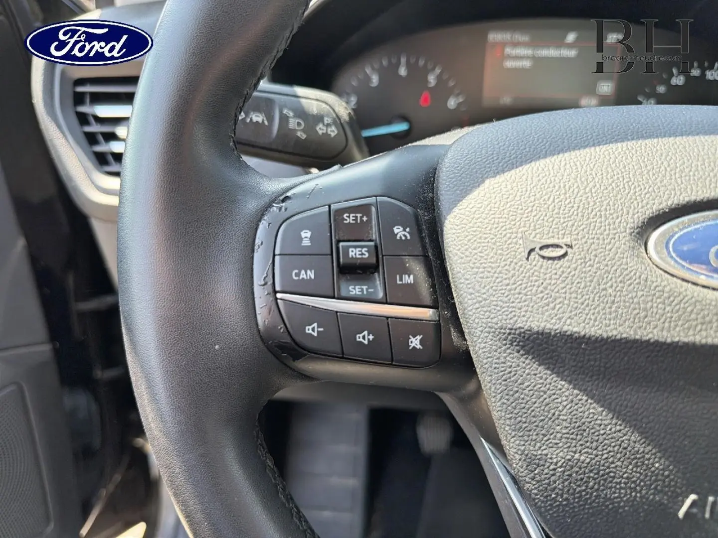 Gros plan sur le volant cuir multifonction noir de la Ford Focus 1.0 Flexifuel, avec commandes de régulateur et volume visibles.
