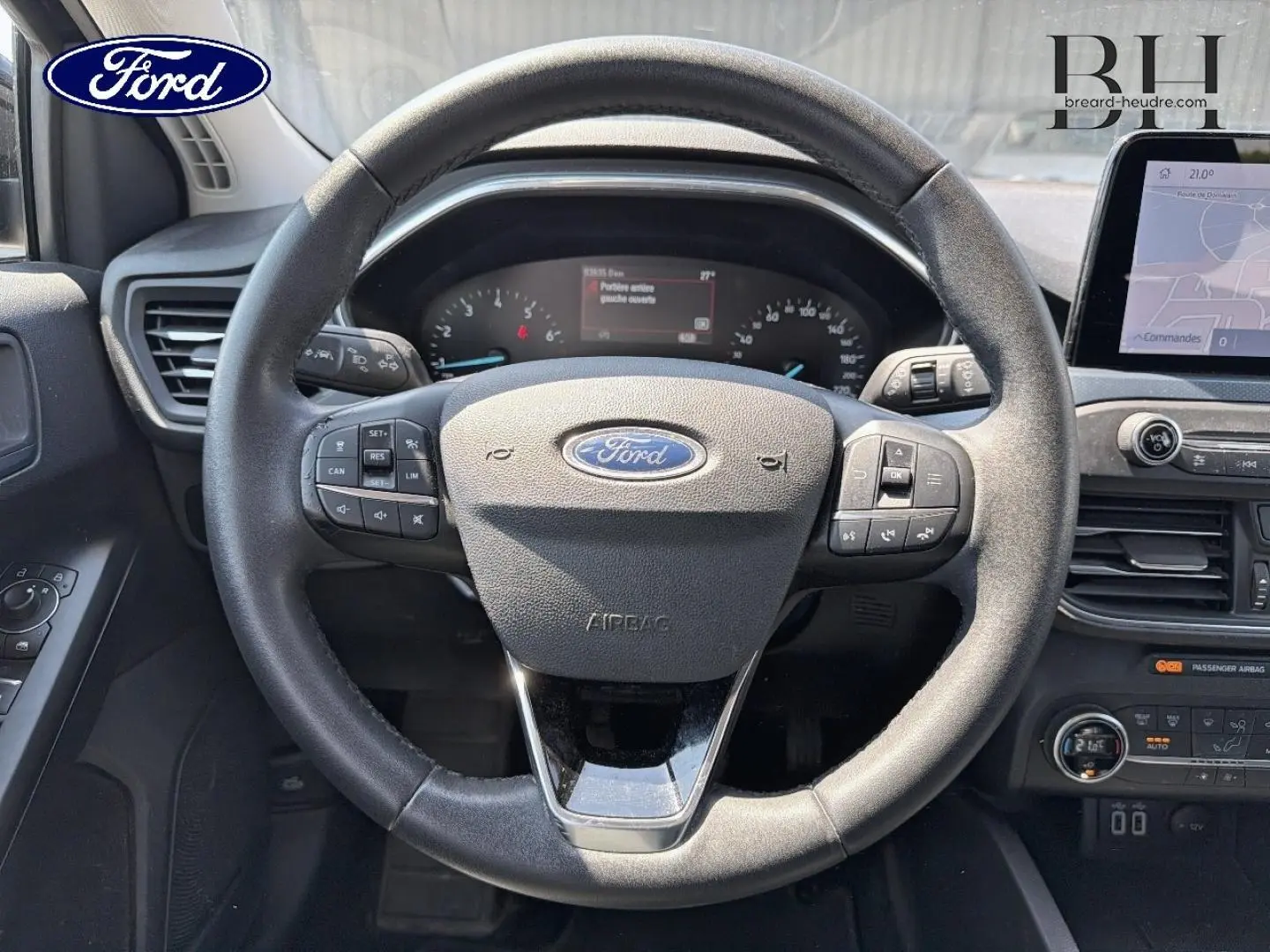 Vue centrée sur le volant cuir noir multifonction de la Ford Focus 1.0 Flexifuel avec tableau de bord et écran tactile visibles.