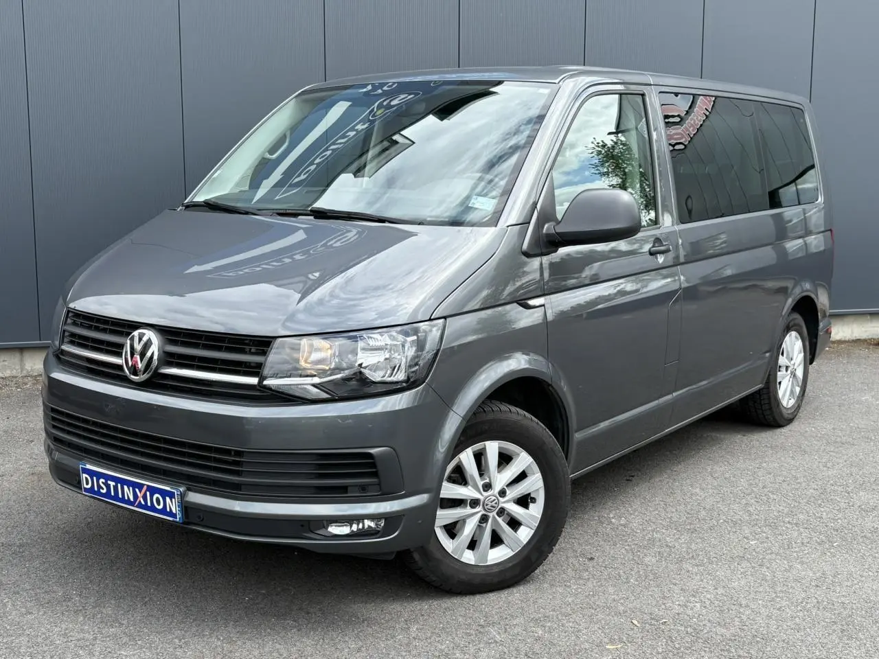 Vue 3/4 avant droit d'un Volkswagen Multivan T6 gris Indium avec jantes alliage et vitres teintées.