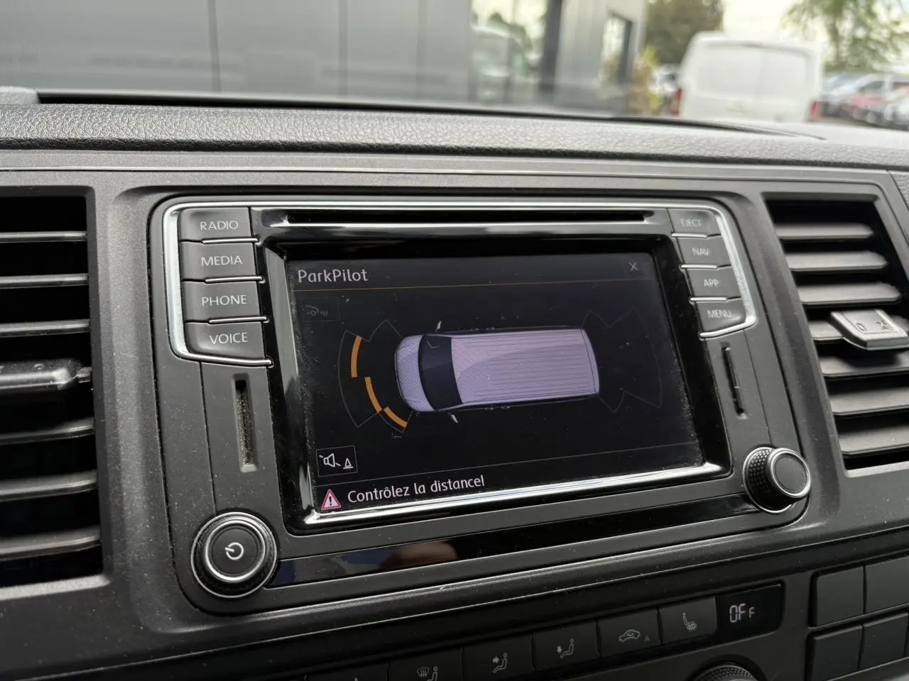 Écran tactile du système ParkPilot dans le tableau de bord du Volkswagen Multivan gris, avec commandes autour.