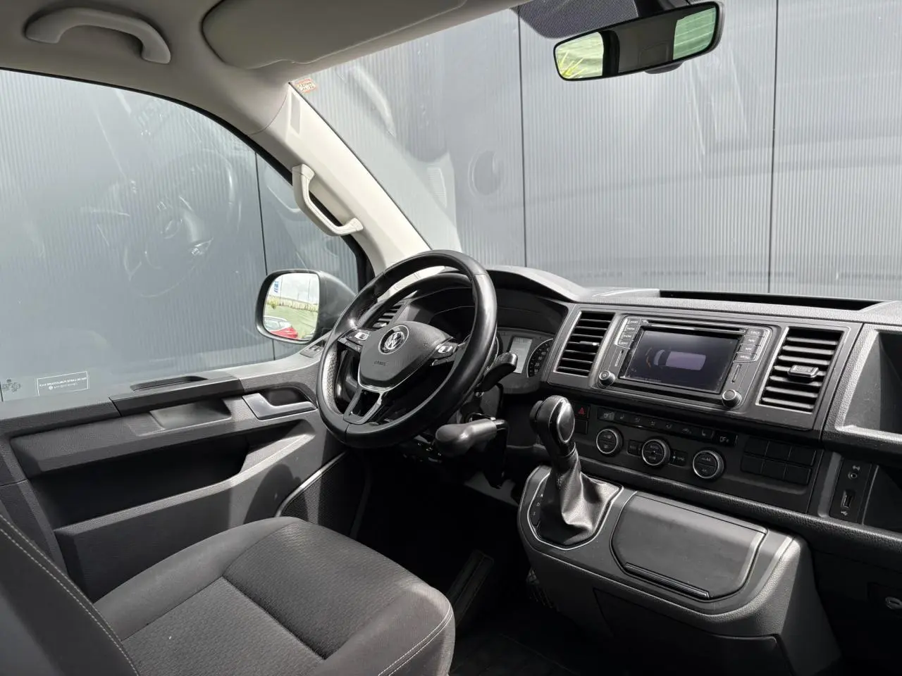 Intérieur avant du Volkswagen Multivan T6 gris Indium, volant cuir multifonction et console centrale avec écran tactile.