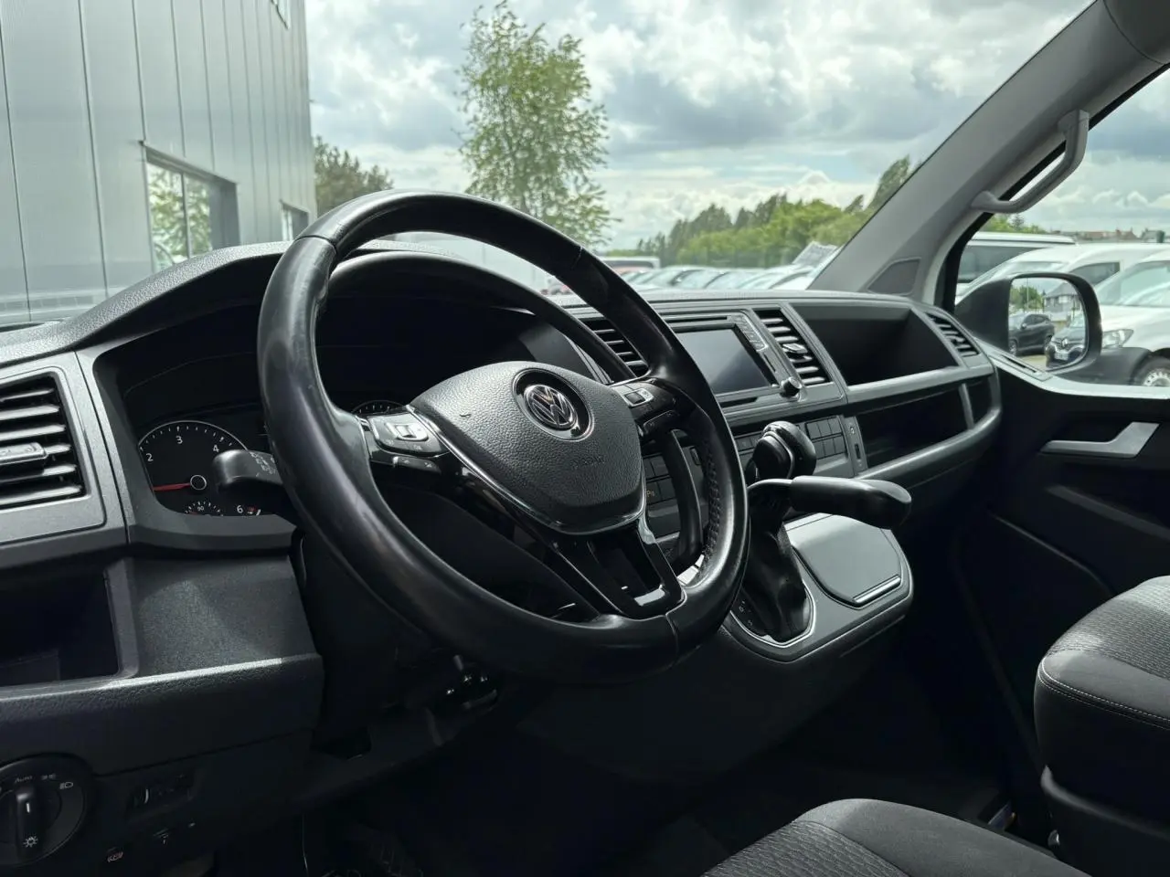 Intérieur du Volkswagen Multivan T6 gris Indium, vue côté conducteur sur le volant cuir multifonction et tableau de bord moderne.