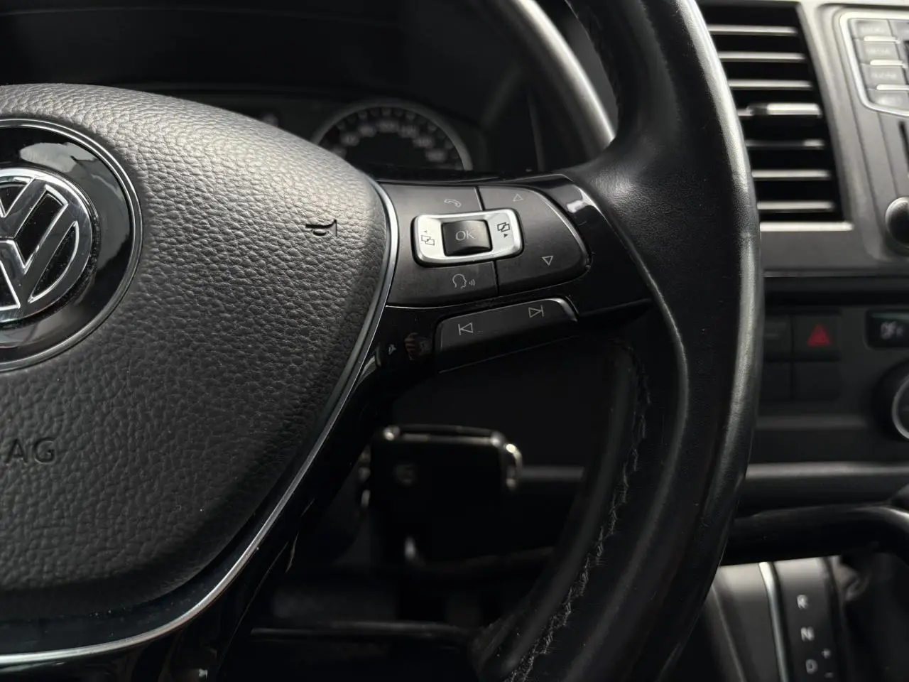 Gros plan sur le volant cuir multifonction noir du Volkswagen Multivan T6 avec commandes intégrées et tableau de bord partiel.