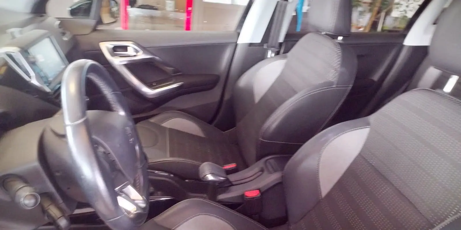 Intérieur noir de la Peugeot 208 2023, vue côté conducteur montrant volant, sièges et console centrale.