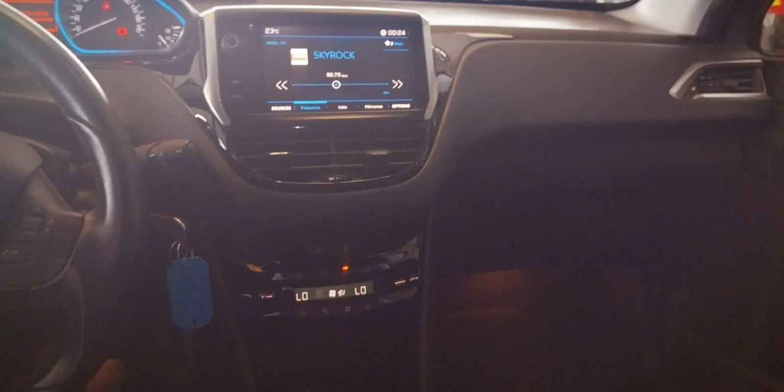 Intérieur noir de la Peugeot 208 2023, vue centrale du tableau de bord avec écran tactile et climatisation digitale allumée.