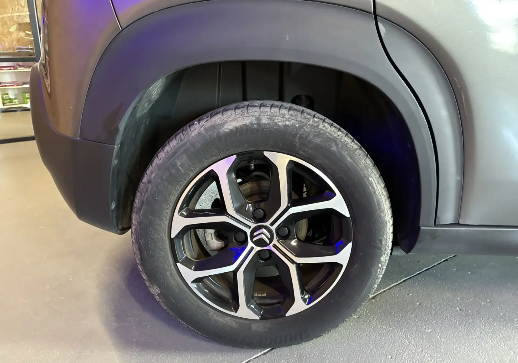 Gros plan sur la roue avant gauche du Citroën C3 Aircross gris platinium avec jante alu bi-ton 16 pouces.