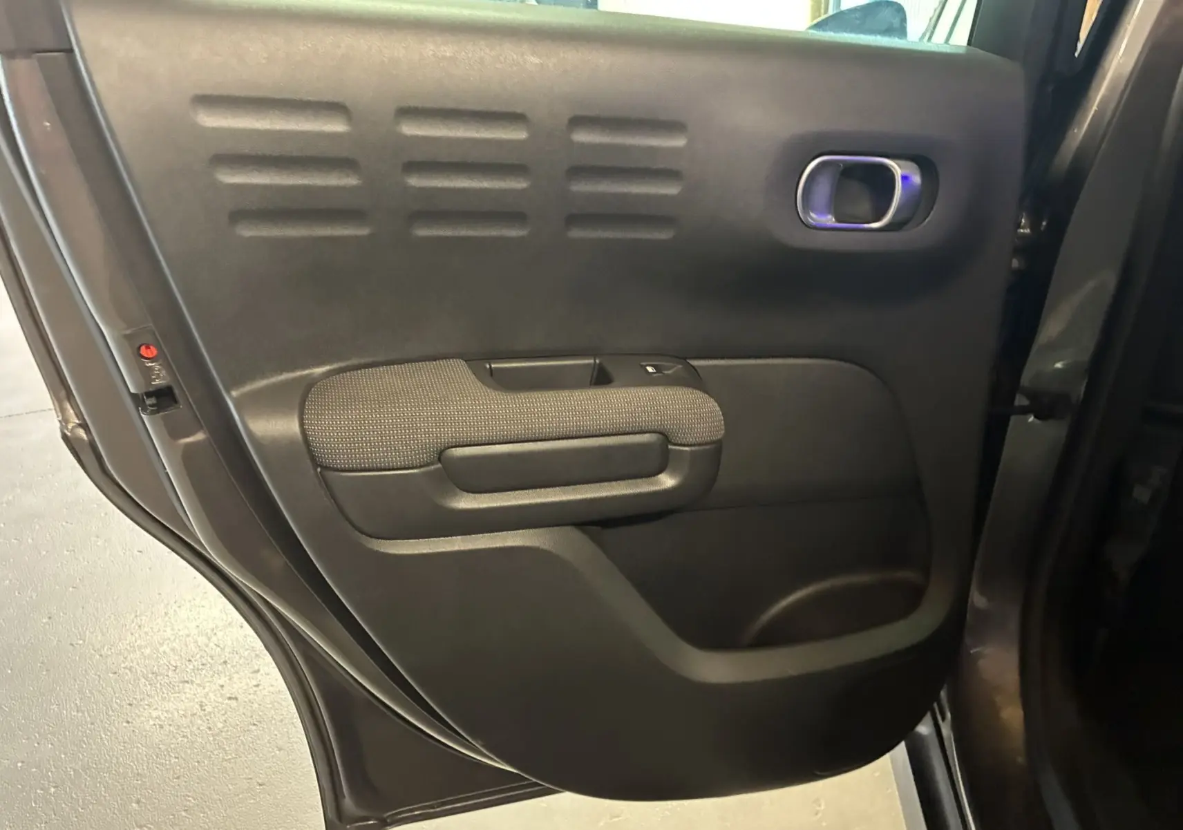 Vue rapprochée de la porte arrière gauche du Citroën C3 Aircross gris platinium métal avec accoudoir en tissu gris noir.