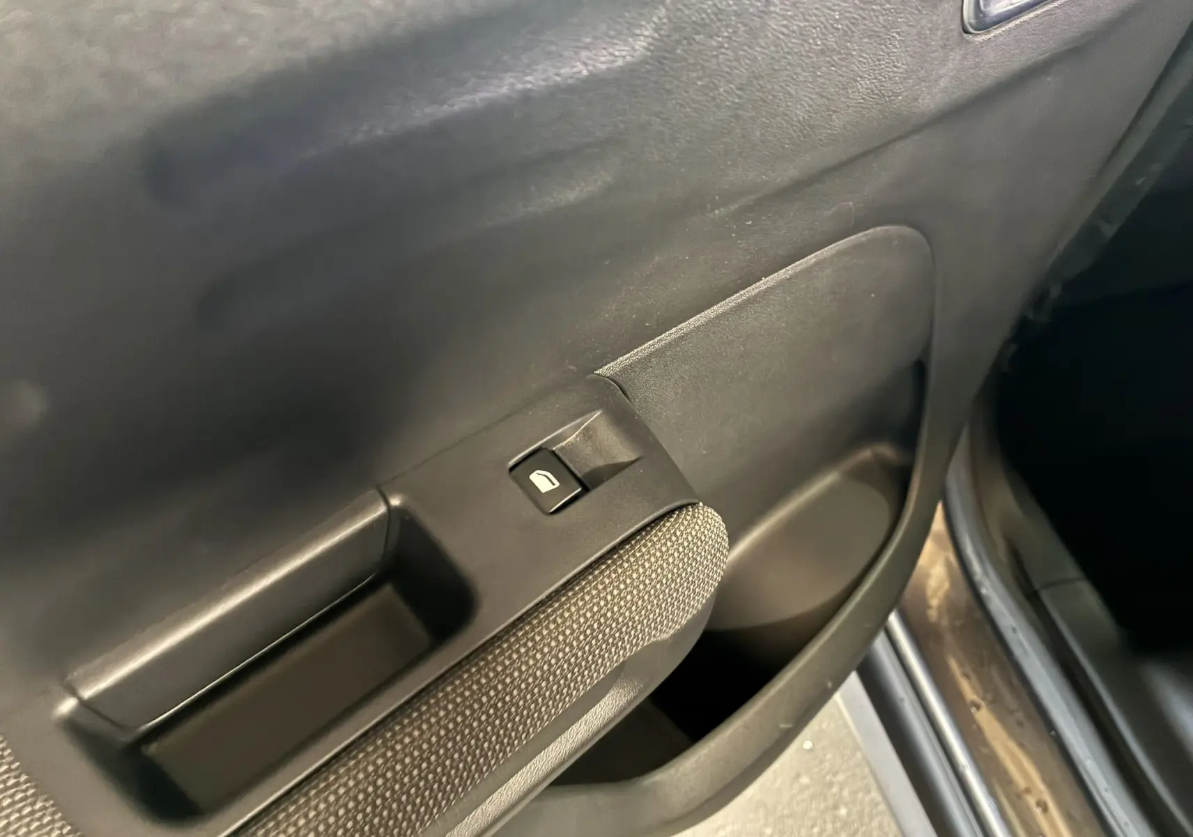 Détail de la commande de lève-vitre sur la portière intérieure côté gauche d'une Citroën C3 Aircross gris platinium.