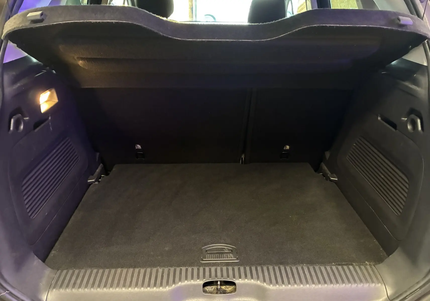Coffre ouvert vu de l'arrière d'une Citroën C3 Aircross 2023, intérieur noir avec éclairage latéral allumé.