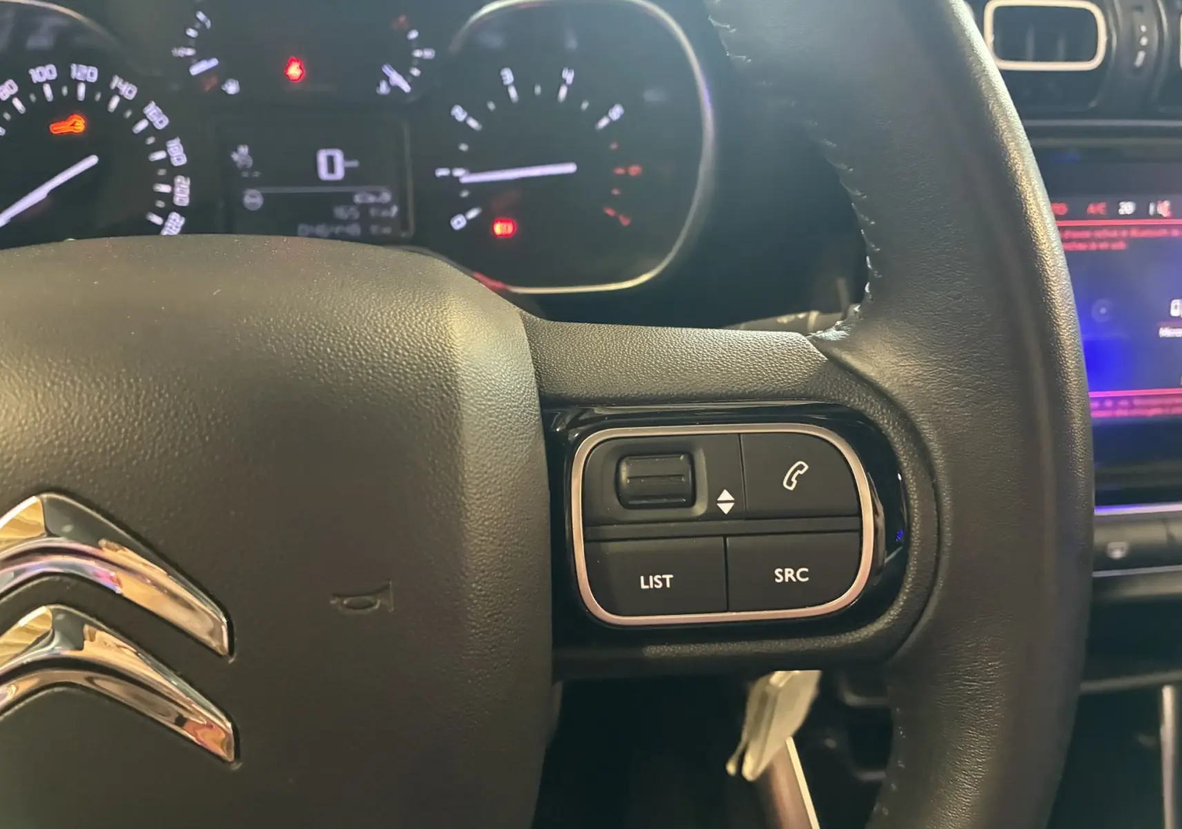 Gros plan sur le volant en cuir multifonction du Citroën C3 Aircross 2023 avec commandes audio et téléphone intégrées.