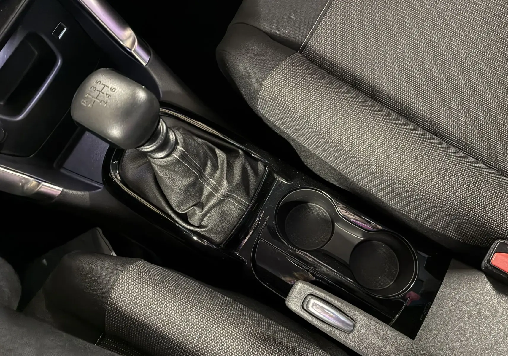 Gros plan sur la console centrale avec levier de vitesse manuel et sièges tissu gris noir de la Citroën C3 Aircross 2023.