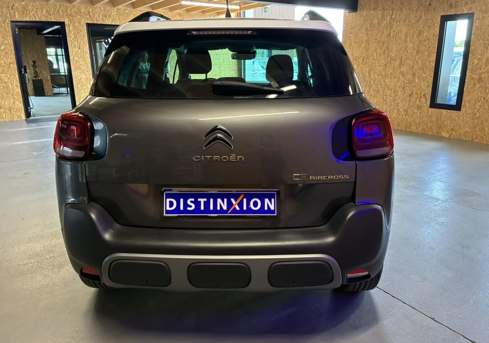 Vue arrière du Citroën C3 Aircross gris platinium métal avec toit blanc et feux arrière LED en intérieur showroom.