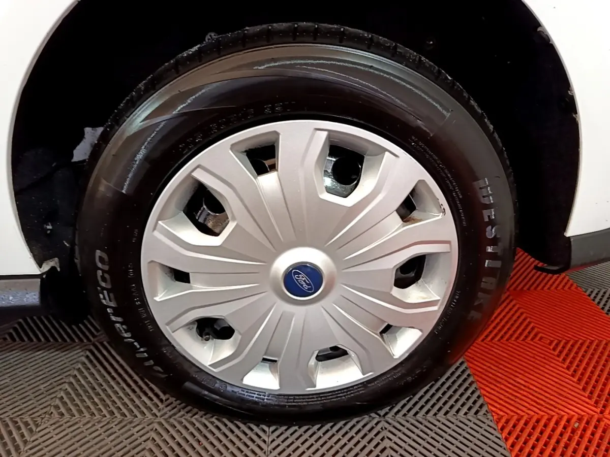 Gros plan sur la roue avant droite du Ford Transit Fourgon blanc, mettant en valeur la jante avec enjoliveur argenté.